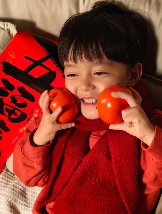 A child celebrating Chinese New Year, taken with OPPO A5 Pro, showcasing vibrant colors and detailed textures.