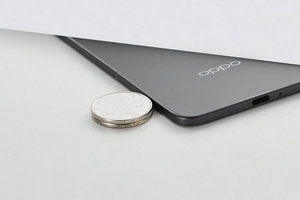 Side profile of the OPPO Find N5 compared to a coin, emphasizing its ultra-thin design.