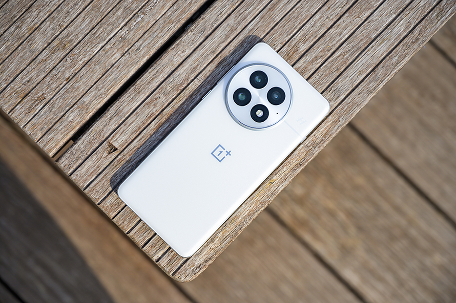 OnePlus 13 placed on a wooden surface, showcasing its elegant white design and camera aesthetics.