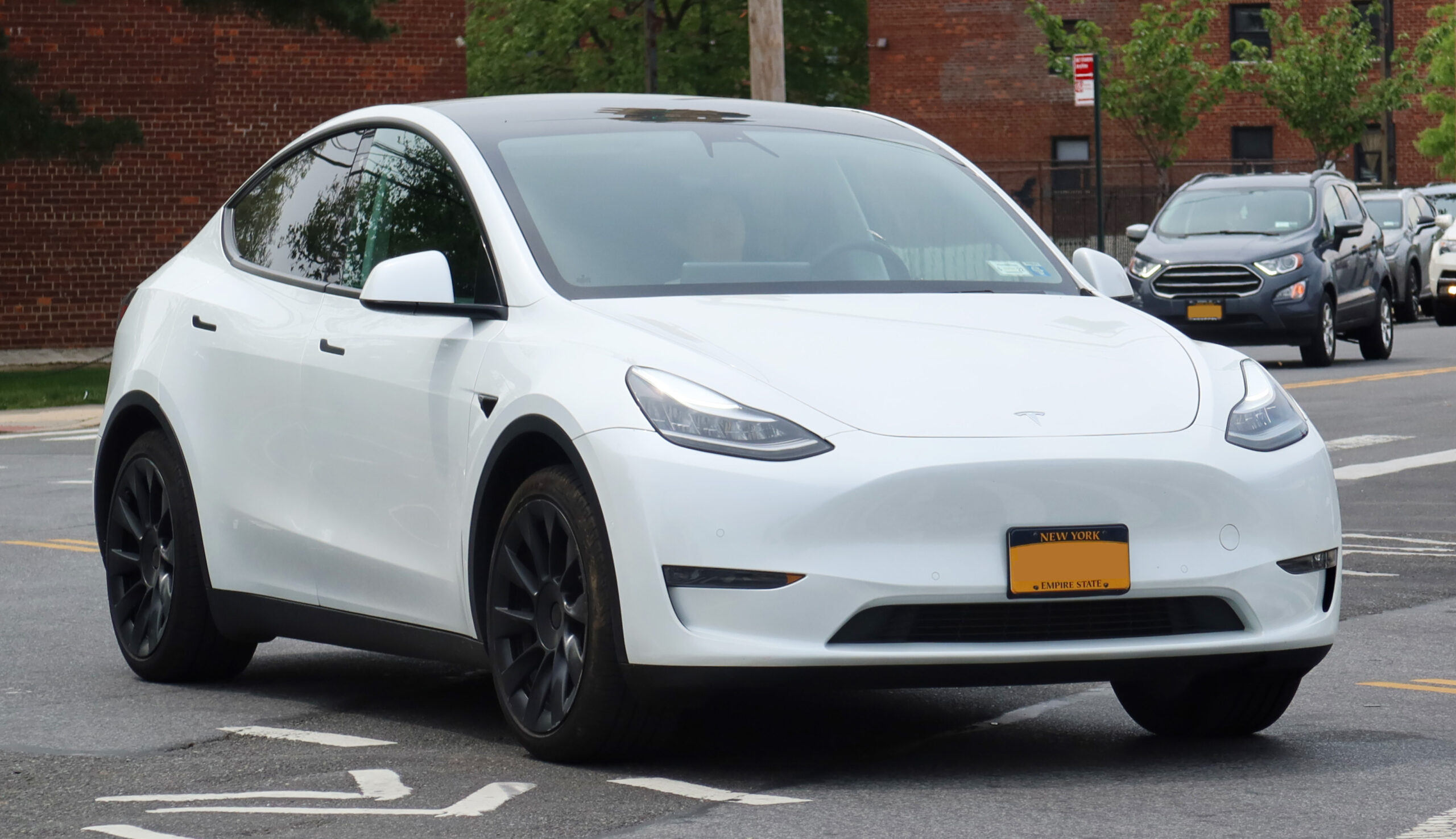 Older version Tesla Model Y parked on a city street, showcasing its sleek and modern design.