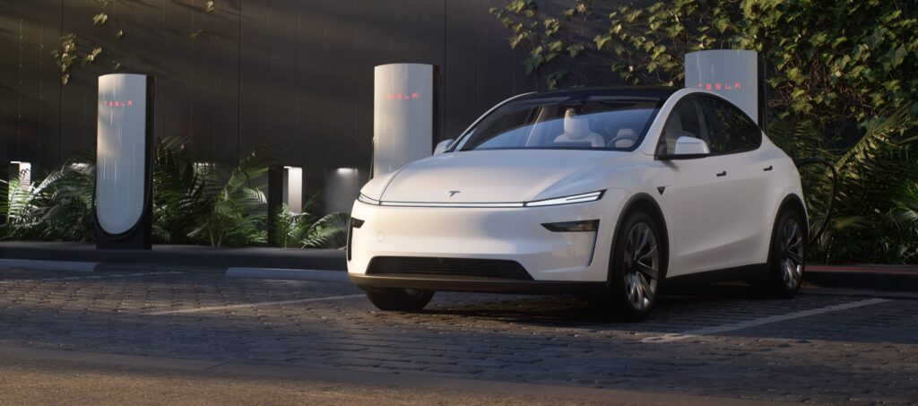 Front view of the Tesla Model Y facelift in white, parked near a modern charging station.