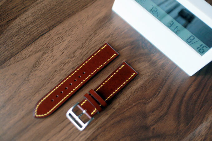 Another overhead look at the band segments on a wooden surface, focusing on the sturdy silver buckle and detailed yellow stitching.