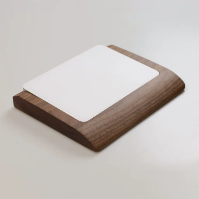 Apple Magic Trackpad resting on a walnut wood wrist rest tray, showcasing its smooth edges and ergonomic design for comfortable use.