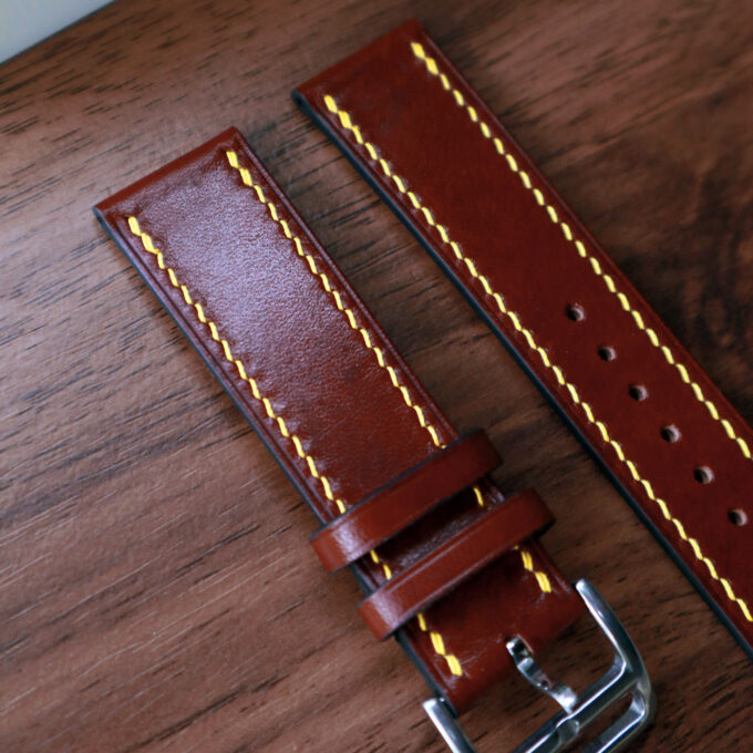 Both strap pieces aligned side by side, revealing the premium brown leather grain and carefully stitched edges.