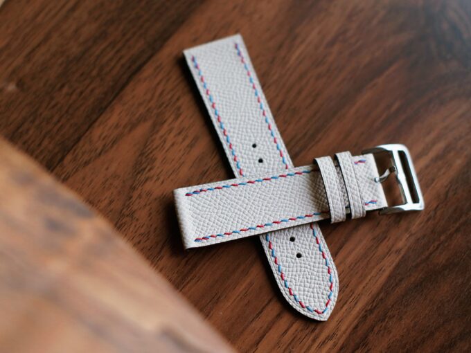 Side perspective showing the stainless steel buckle, keepers, and the underside of the white leather band.