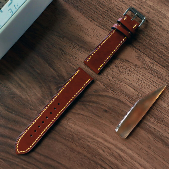 Angled shot showing the fully extended band’s perforations and polished metal hardware, set against a wooden desk.