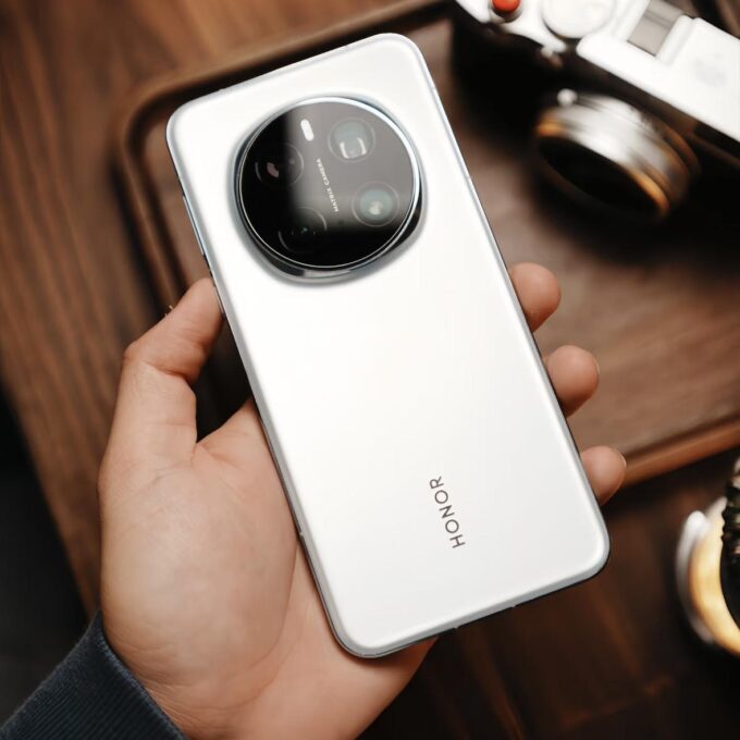 Honor Magic 7 Pro smartphone in white color, shown being held in hand, showcasing its sleek design and circular rear camera module.