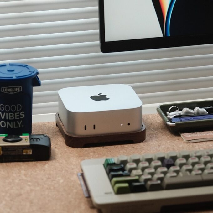 Desktop setup with a Mac Mini M4 placed on a stylish walnut stand, surrounded by retro and modern accessories.