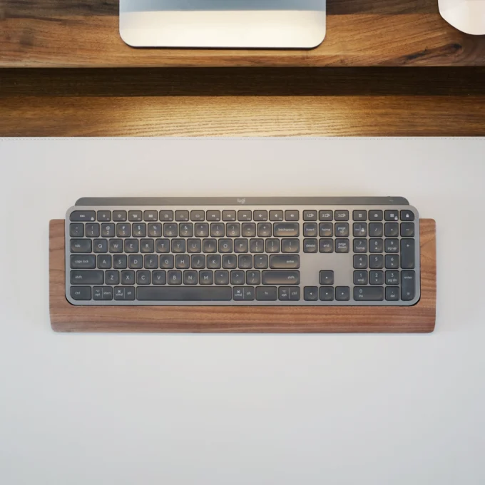 Top-down image showing the Walnut Wood Wrist Rest Tray aligned perfectly under the Logitech MX Keys keyboard, revealing the tray’s protective platform and natural wood texture.