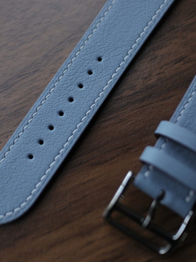 Extreme close-up of the blue strap’s underside near the buckle, showcasing the smooth tan finish.