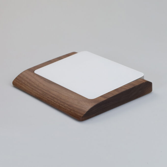 Angled view of the walnut wood wrist rest tray designed for the Apple Magic Trackpad, with contoured edges for ergonomic wrist support.