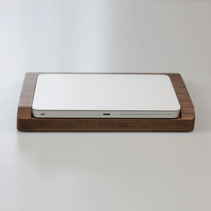 Flat profile view of the Apple Magic Trackpad on a solid walnut wood wrist rest tray, demonstrating its minimalist and functional aesthetic.