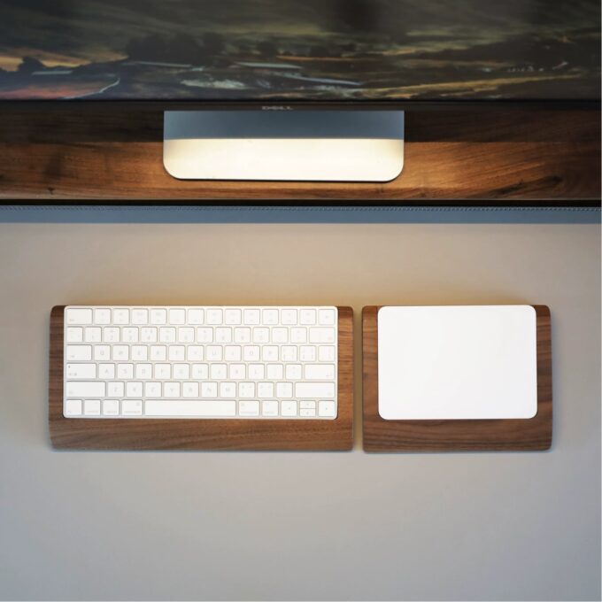 A seamless desk setup featuring a Magic Keyboard and trackpad, both paired with wooden wrist rest trays for an ergonomic and stylish workspace.