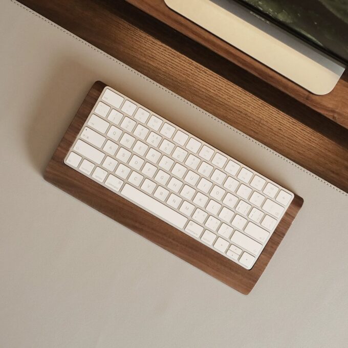 Overhead shot of a Magic Keyboard on a wooden wrist rest tray, showcasing its minimalistic and modern design aesthetic.