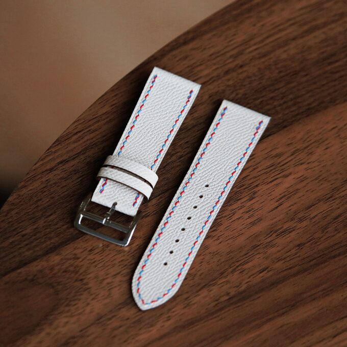 Close-up emphasizing the neat stitching and clean edges of the white leather band on a wood background.