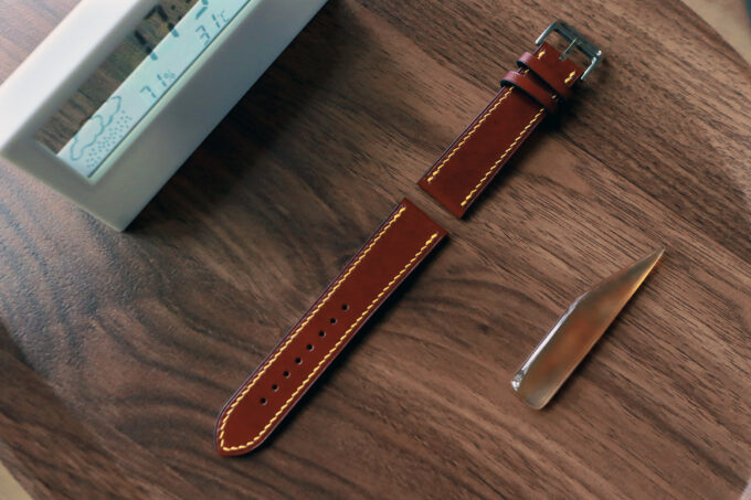 Angled shot showing the fully extended band’s perforations and polished metal hardware, set against a wooden desk.