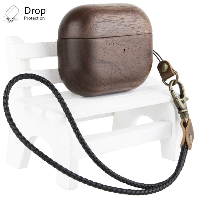 A walnut wood AirPods case placed on a white chair, featuring a smooth finish and an attached black leather strap, emphasizing drop protection.