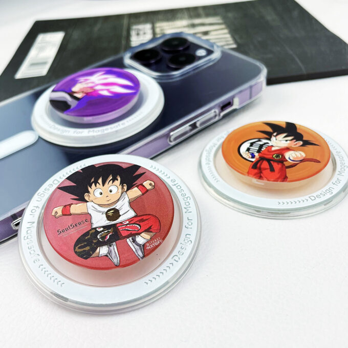 Several Dragon Ball-themed MagSafe grips laid out next to a phone case, including one with Kid Goku artwork on a red background.