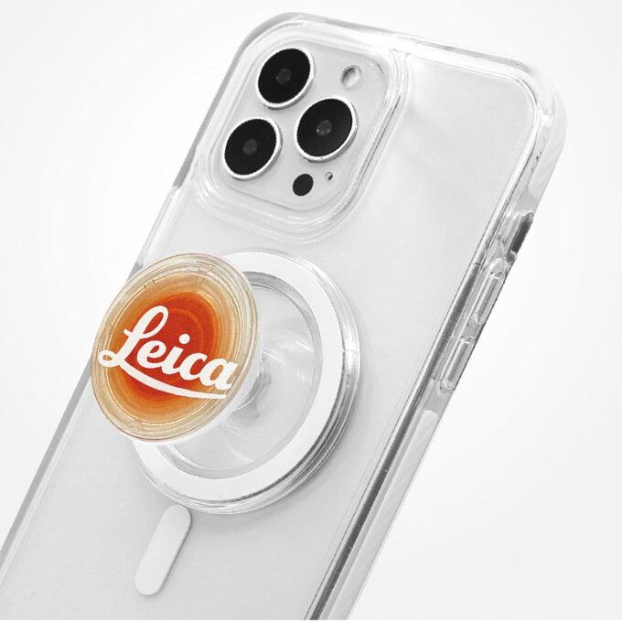 A clear-cased iPhone Pro fitted with a semi-translucent “Leica” MagSafe grip, highlighting its minimal, branded design.