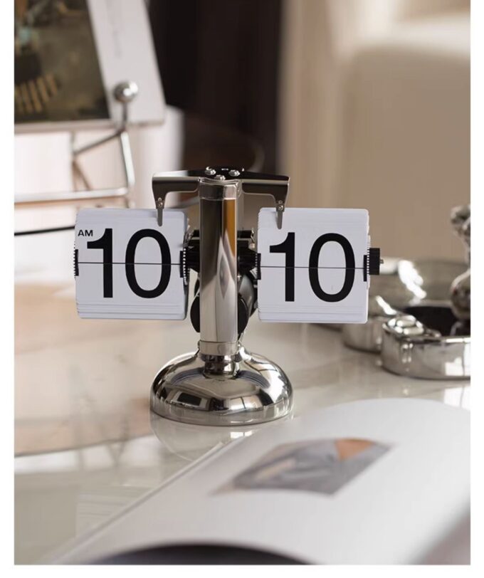 A stylish silver mechanical flip clock sitting on a modern desk, blending vintage charm with contemporary decor.
