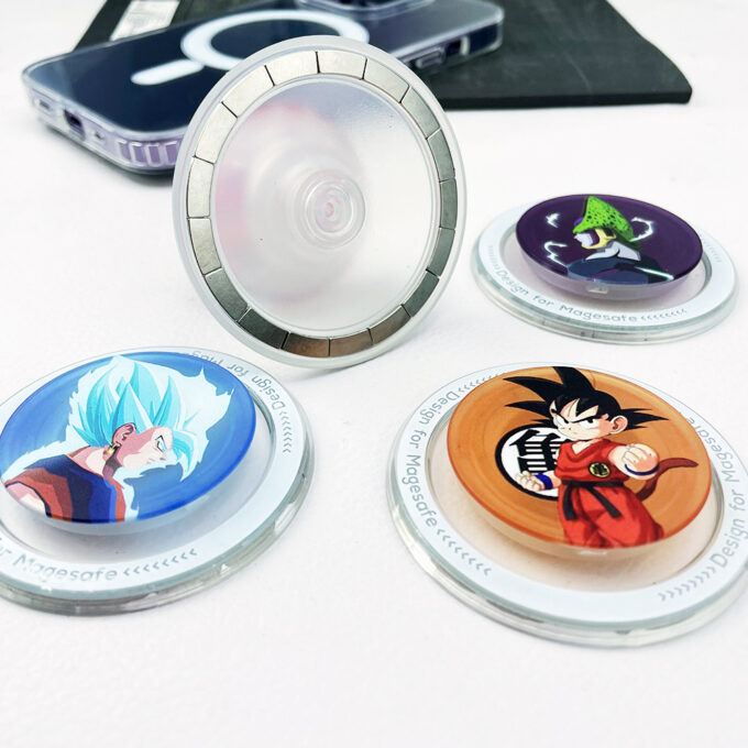 A partially extended grip demonstrating its foldable stand feature, surrounded by additional Goku-themed designs on a table.