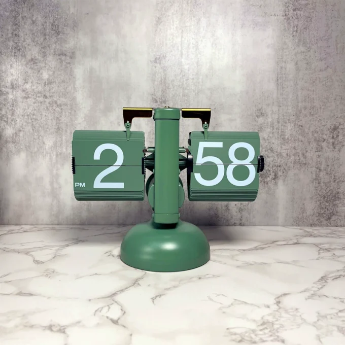An avocado green mechanical flip desk clock with a retro design, standing out against a stylish marble surface.