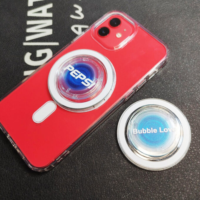 A red iPhone featuring a Pepsi-branded MagSafe grip, displayed next to a “Bubble Love” design ring.