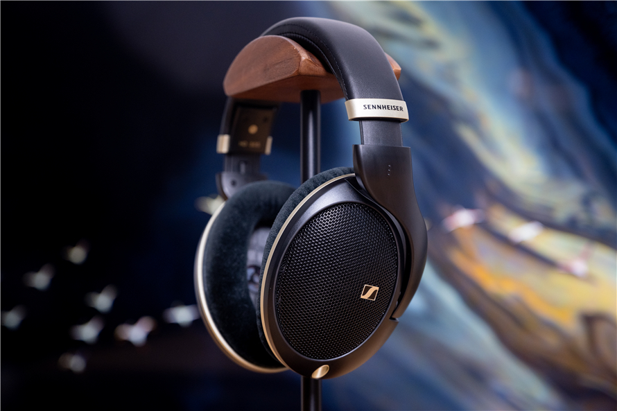 Angled perspective of the Sennheiser HD 505 headphones on a stand, highlighting the open-back ear cup design, velour ear pads, and the natural wood accents on the headband against a soft, blurred background.