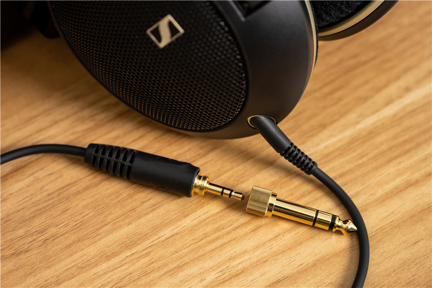 Side view of the Sennheiser HD 505 headphones on a wooden surface, focusing on the detachable 1.8-meter cable with a swappable 6.35mm/3.5mm jack, showcasing the practical accessory included with the headphones.