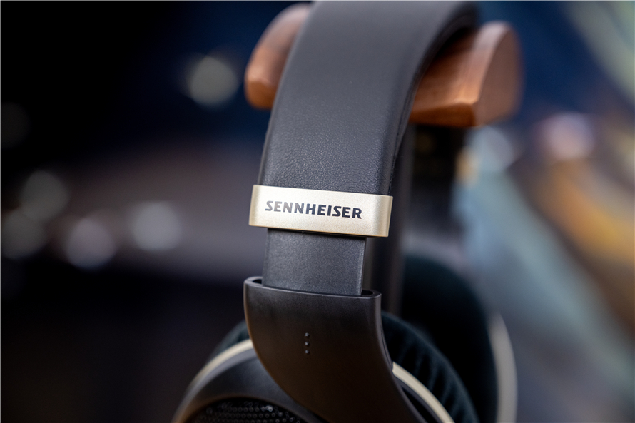 Detailed view of the Sennheiser HD 505's leather-wrapped headband with the Sennheiser branding in gold, highlighting the plush velour ear pads and the adjustable headband's modern ergonomic design against a dark background.